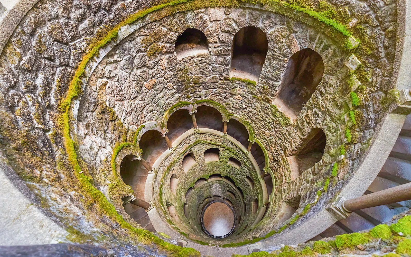 Quinta da Regaleira Initiation Well in Sintra, Portugal, with moss-covered stone walls.