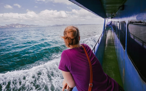 Woman gazing at the Andaman Sea from a cruise ship deck.