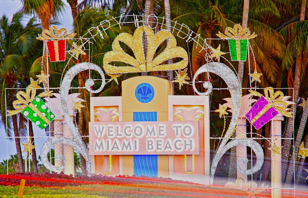 Welcome sign at Miami Beach with Christmas decorations and palm trees.