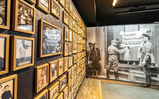 Wall of historical photos at Caen Memorial Museum, depicting World War II events and Nazi propaganda.