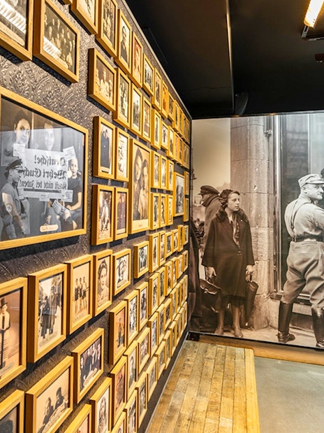 Wall of historical photos at Caen Memorial Museum, depicting World War II events and Nazi propaganda.