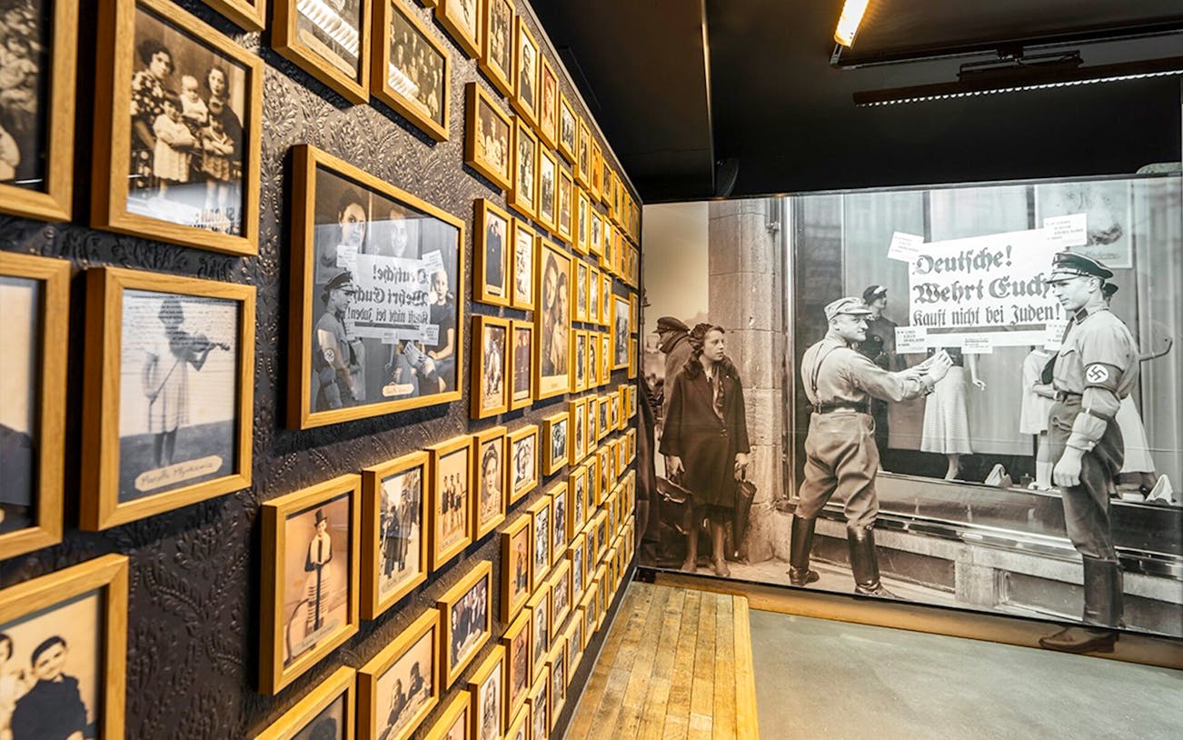 Wall of historical photos at Caen Memorial Museum, depicting World War II events and Nazi propaganda.