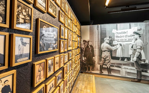 Wall of historical photos at Caen Memorial Museum, depicting World War II events and Nazi propaganda.