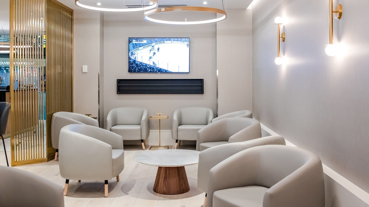 Seating area in Plaza Premium Lounge at Vancouver International Airport with TV and modern decor.