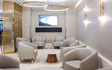 Seating area in Plaza Premium Lounge at Vancouver International Airport with TV and modern decor.