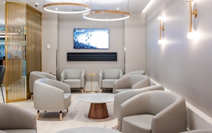Seating area in Plaza Premium Lounge at Vancouver International Airport with TV and modern decor.