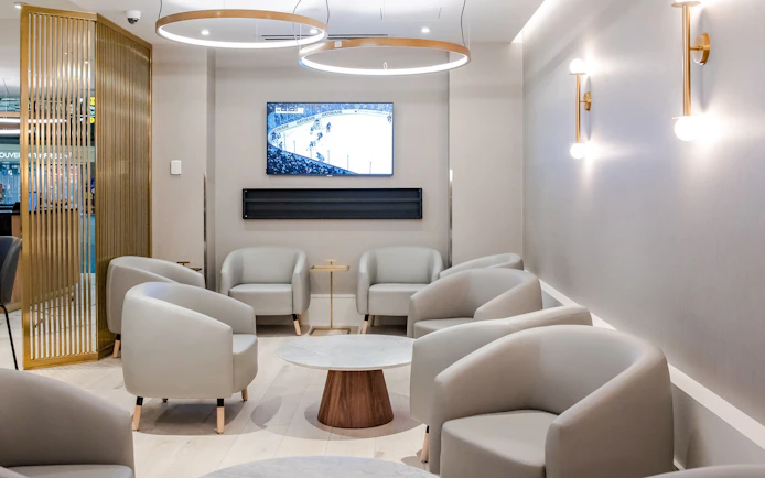 Seating area in Plaza Premium Lounge at Vancouver International Airport with TV and modern decor.