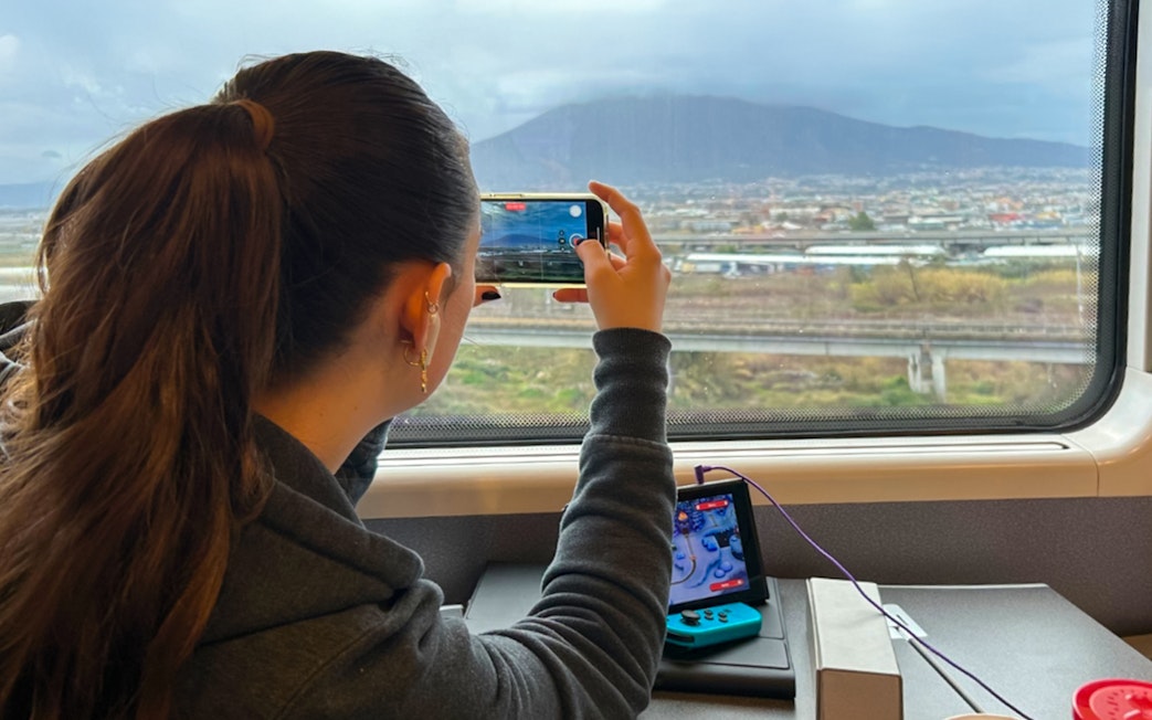 Woman photographing landscape from train window with a smartphone.