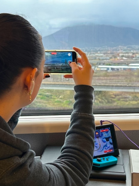 Woman photographing landscape from train window with a smartphone.