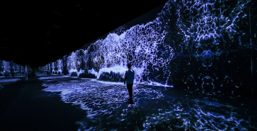 Person walking through ARTE Museum Dubai's Starry Beach exhibit with digital waves.
