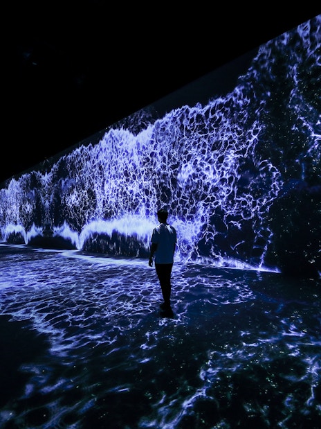 Person walking through ARTE Museum Dubai's Starry Beach exhibit with digital waves.