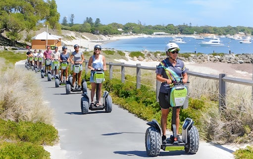 Tourists on Segways exploring Rottnest Island with a ferry visible in the background.