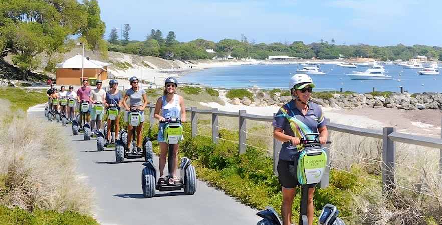 Tourists on Segways exploring Rottnest Island with a ferry visible in the background.