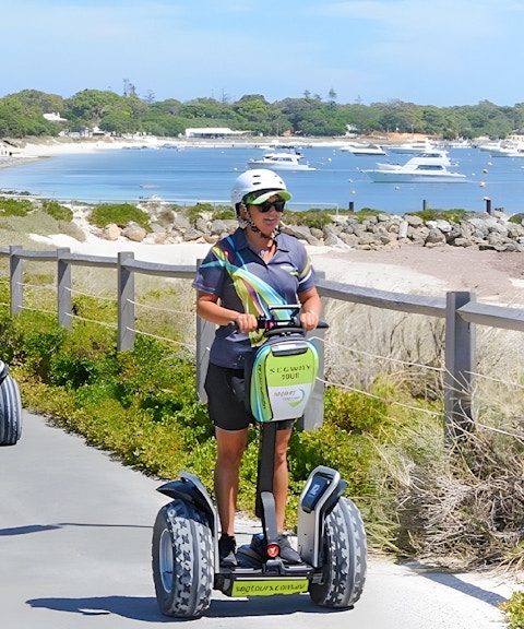 Tourists on Segways exploring Rottnest Island with a ferry visible in the background.