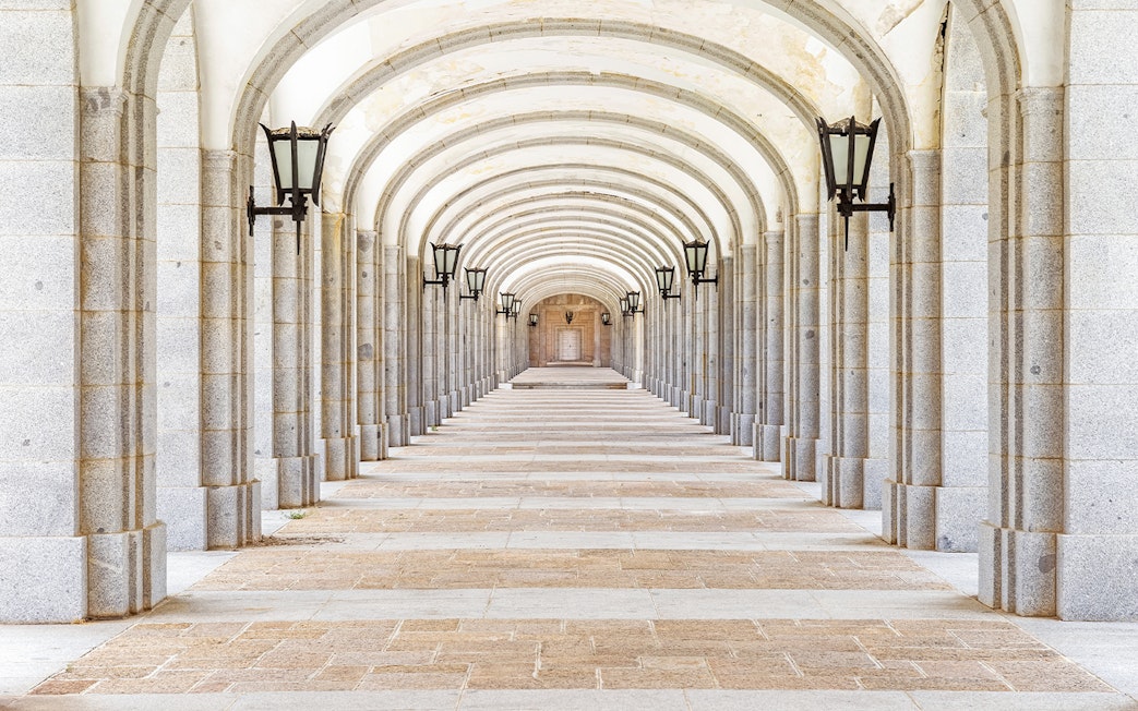 Covered stone corridor with arches and lamps in Valley of the Fallen, Valle de los Caidos, Spain.