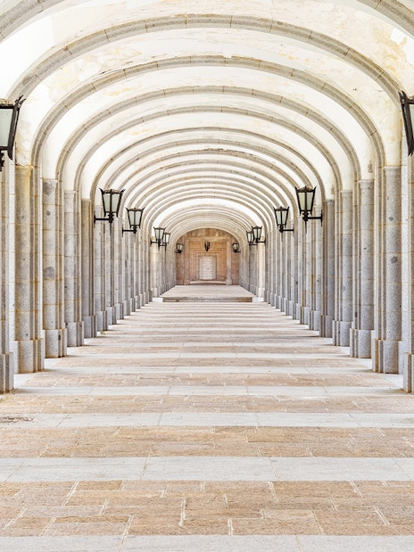 Covered stone corridor with arches and lamps in Valley of the Fallen, Valle de los Caidos, Spain.