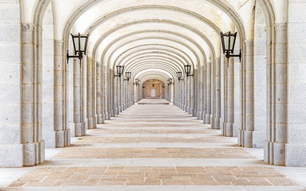 Covered stone corridor with arches and lamps in Valley of the Fallen, Valle de los Caidos, Spain.