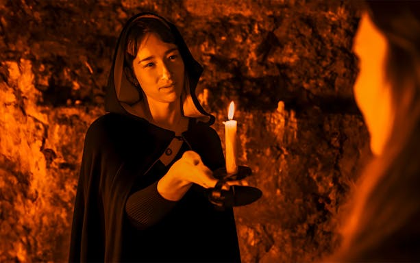 Guide holding candle in Blair Street Underground Vaults with guest.
