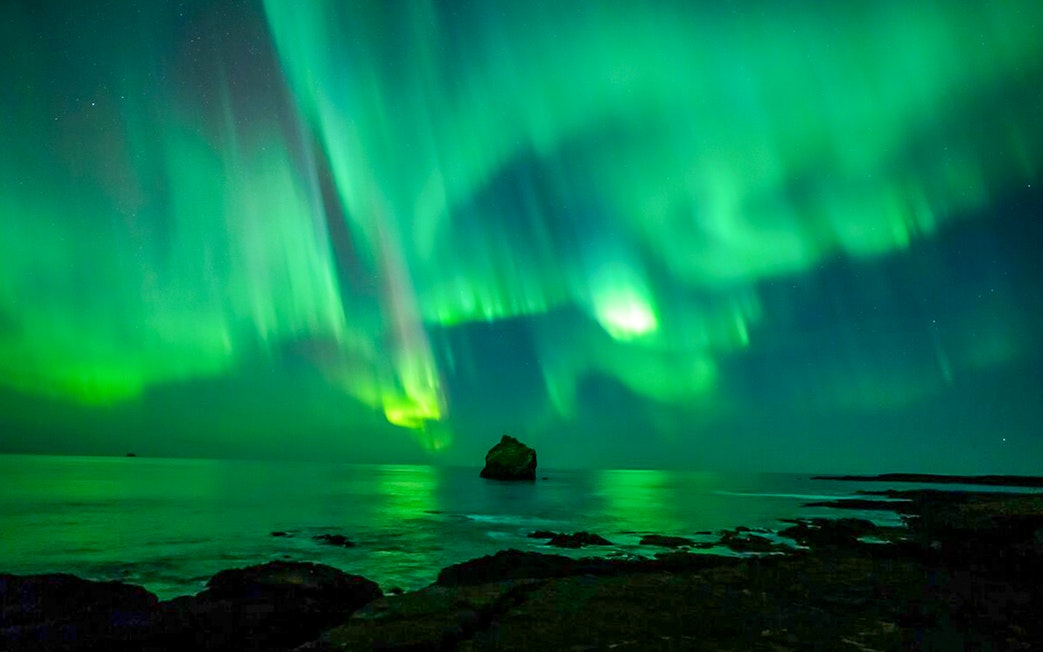 Northern lights over ocean during Premium Northern Lights Super Jeep Tour.