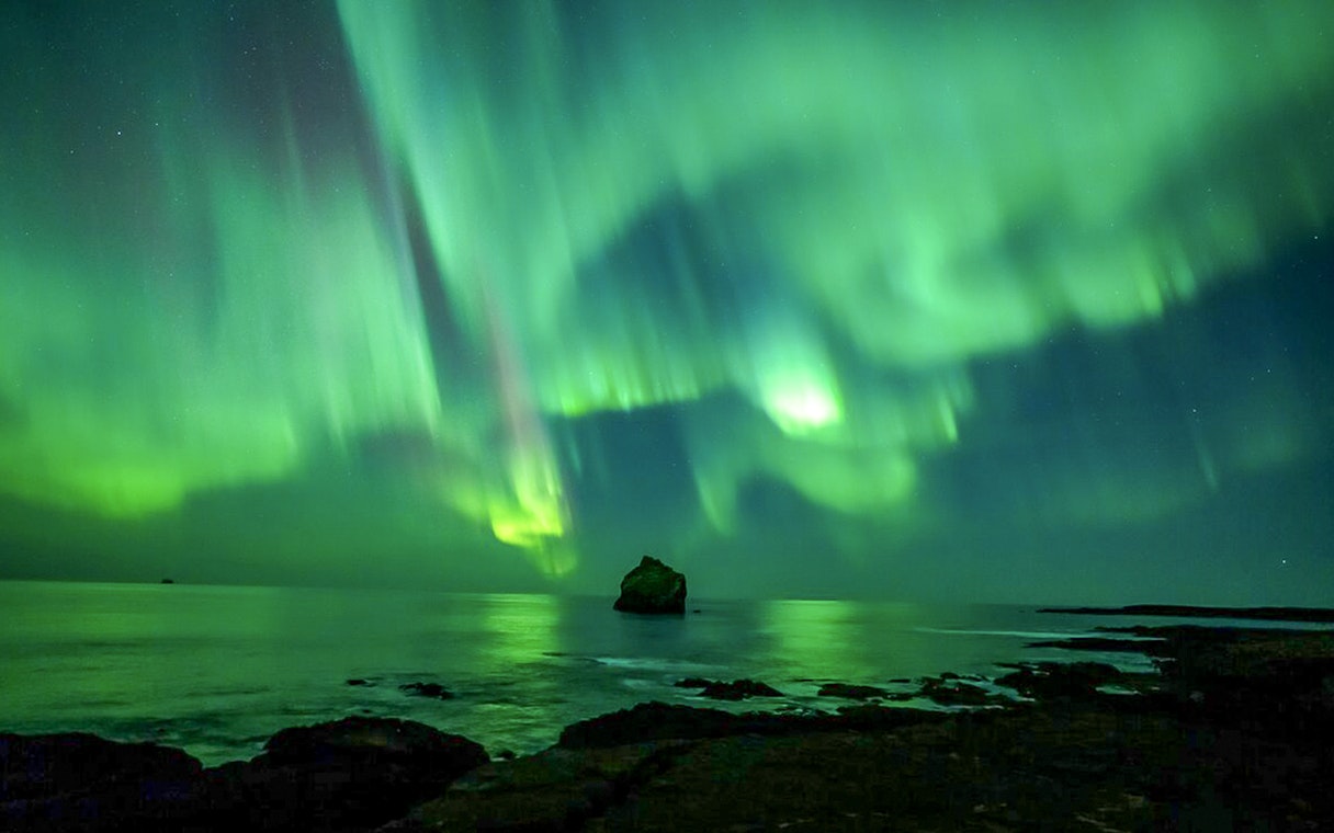 Northern lights over ocean during Premium Northern Lights Super Jeep Tour.
