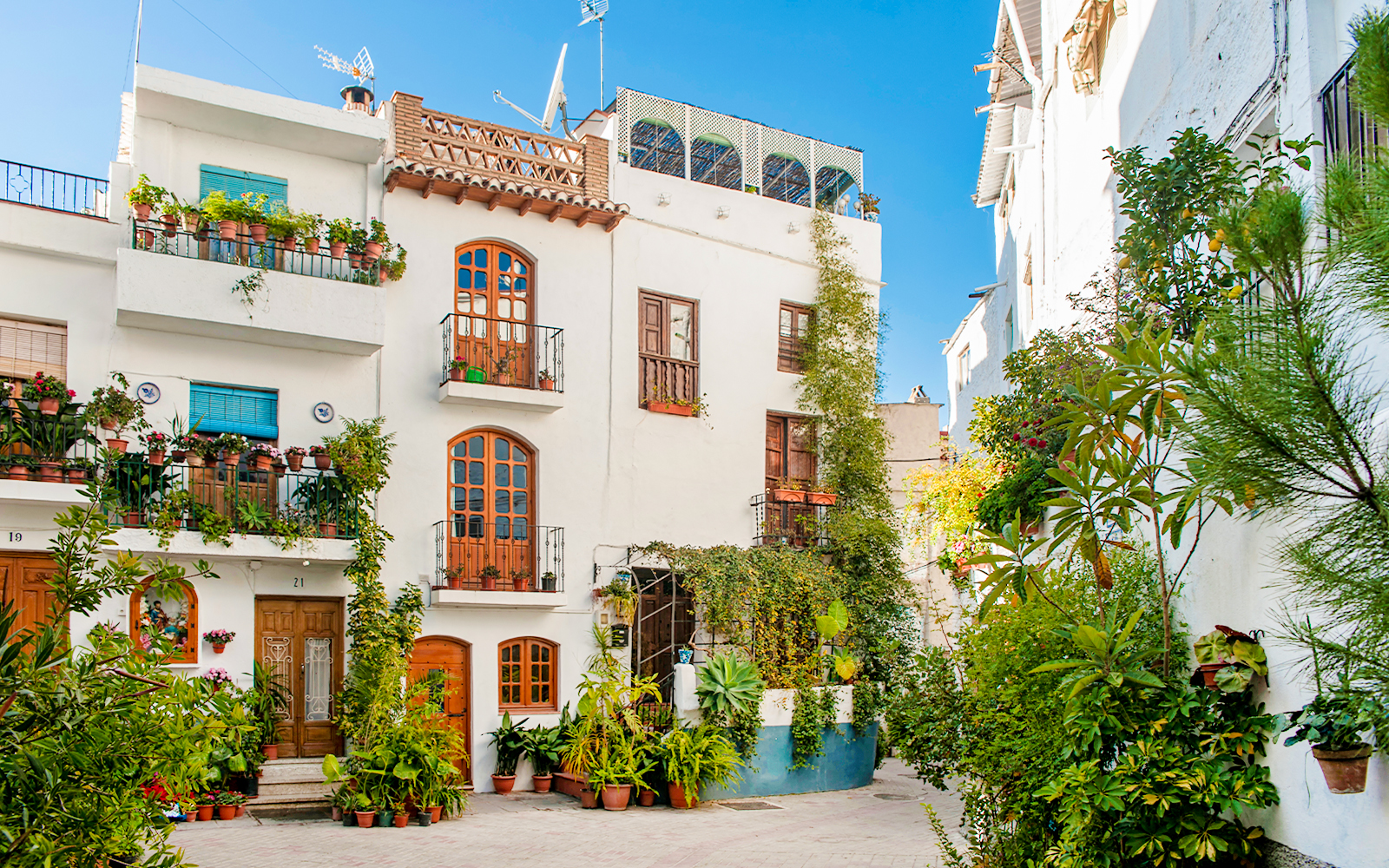 Street view of whitewashed buildings with potted plants in Lanjarón, Granada, Andalusia.