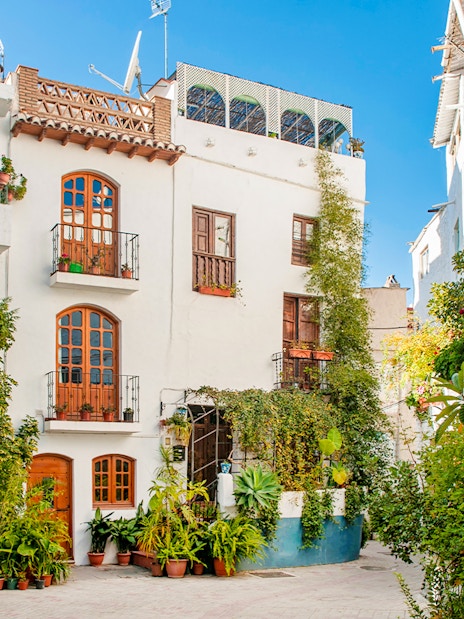 Street view of whitewashed buildings with potted plants in Lanjarón, Granada, Andalusia.