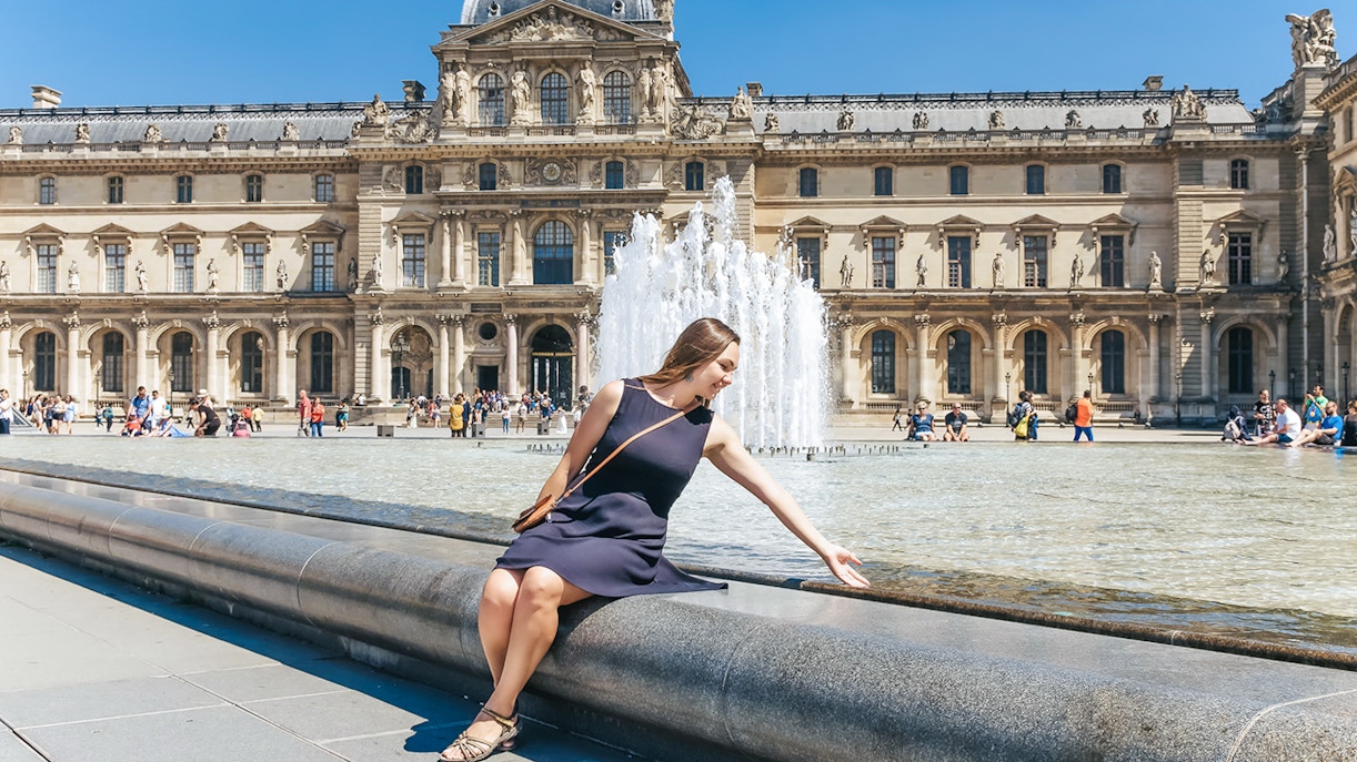 Girl sitting by Louvre Museum fountain in Paris, ideal spot for day trip tour.
