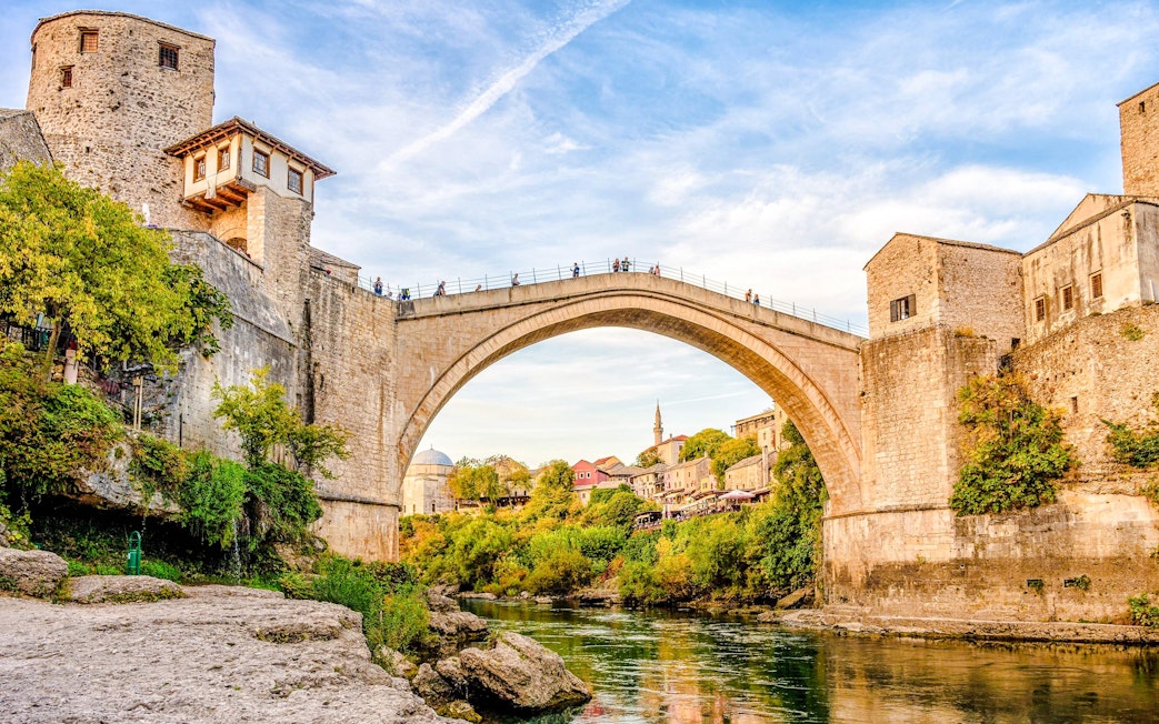 Stari Most bridge in Mostar, Bosnia, spanning the Neretva River with surrounding historic buildings.