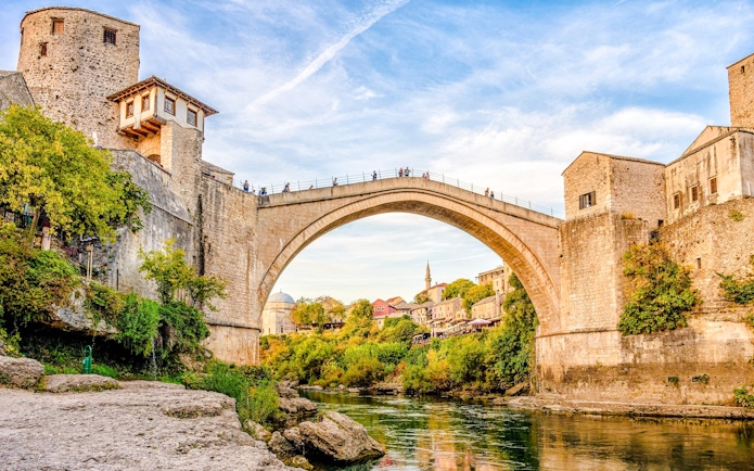 Stari Most bridge in Mostar, Bosnia, spanning the Neretva River with surrounding historic buildings.