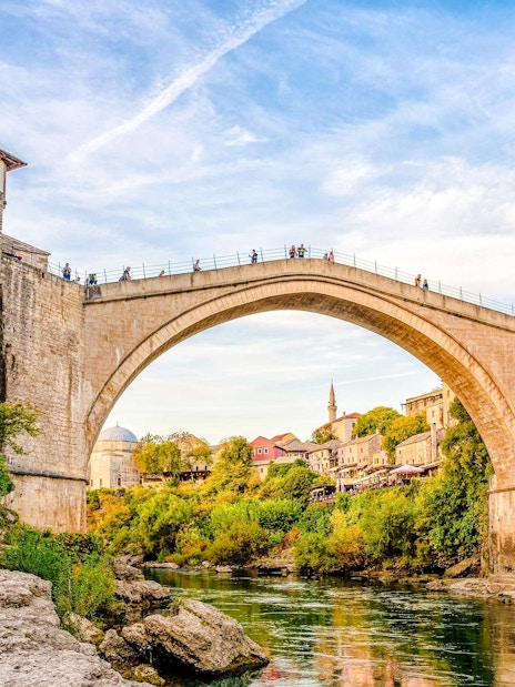 Stari Most bridge in Mostar, Bosnia, spanning the Neretva River with surrounding historic buildings.