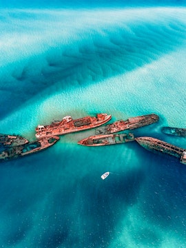 Shipwrecks in turquoise waters near Moreton Island, Australia, with a boat nearby.