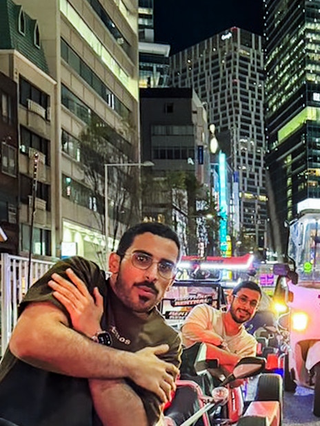 Tourists in go-karts on a busy Tokyo street at night.