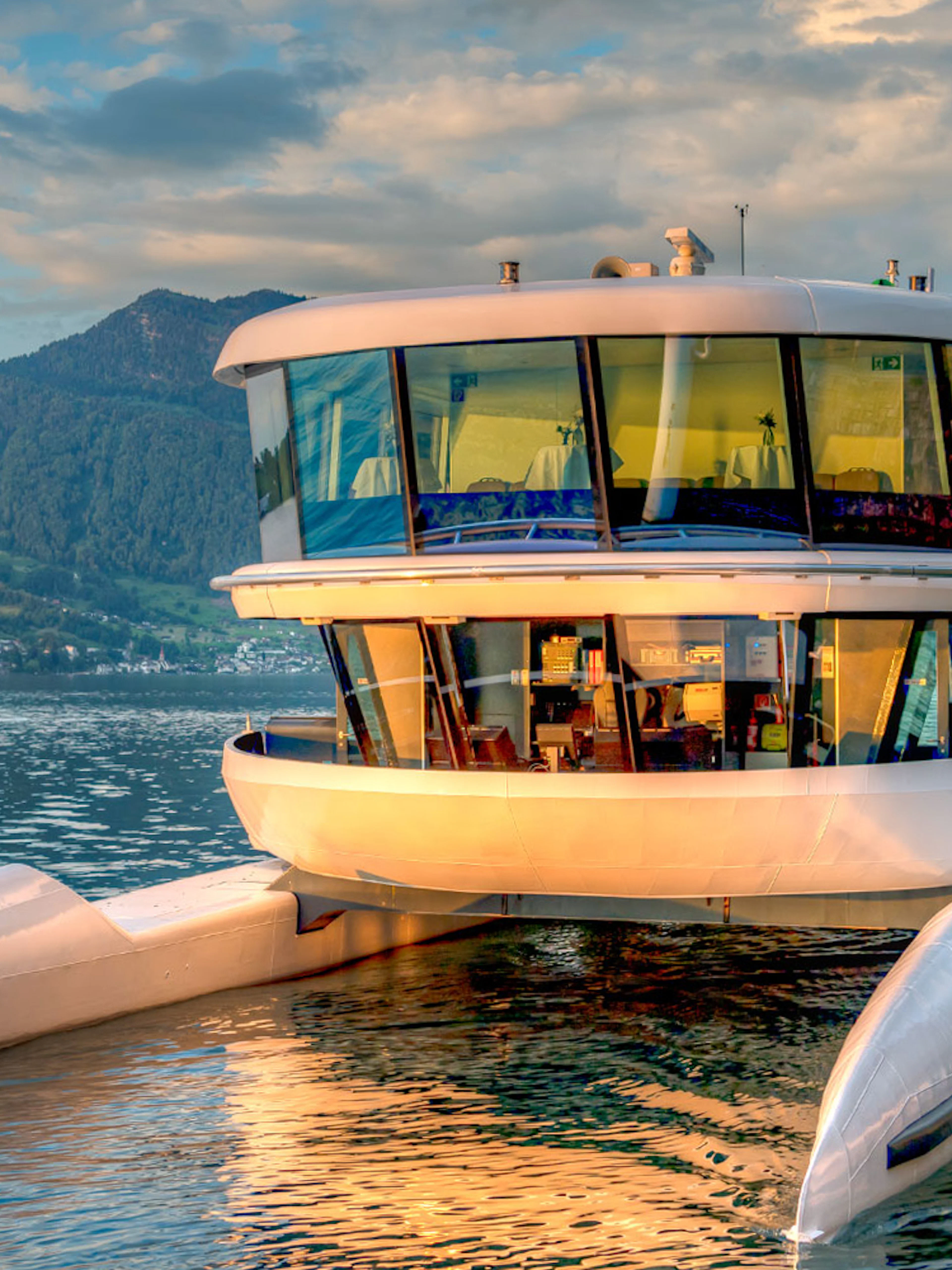 Catamaran docked on a serene lake with mountain backdrop.