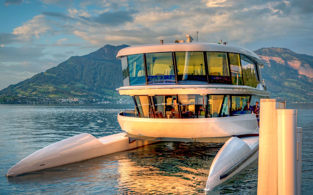 Catamaran docked on a serene lake with mountain backdrop.