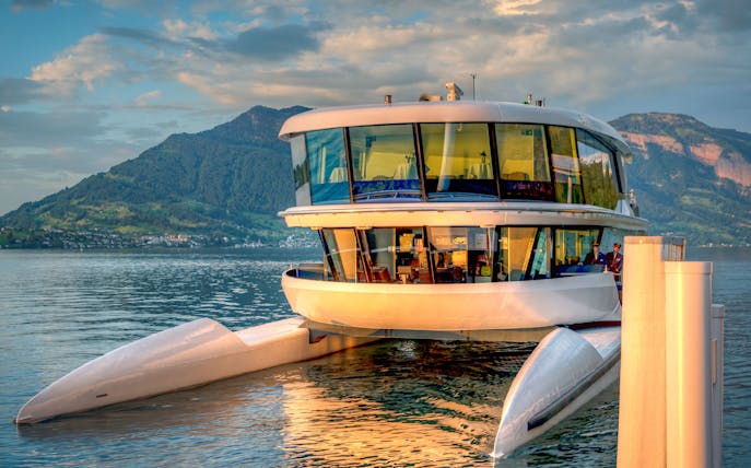 Catamaran docked on a serene lake with mountain backdrop.