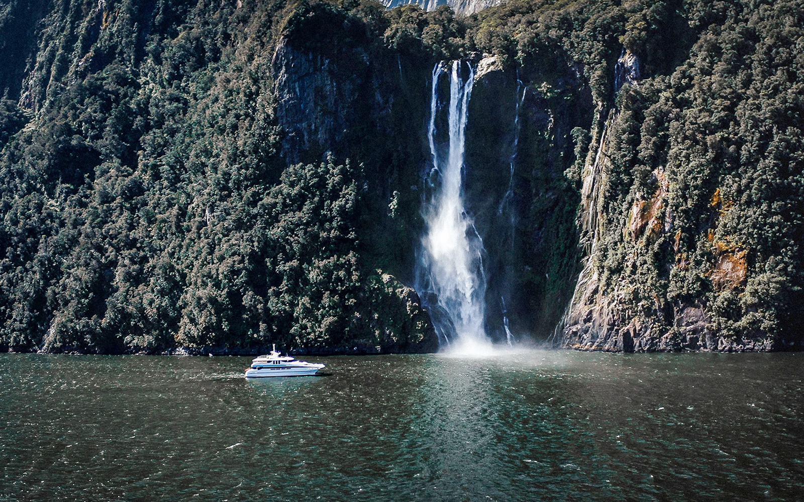 Cruise ship approaching a waterfall in Milford Sound