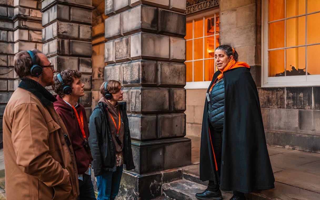 Tour guide leading an evening group in Edinburgh Old Town.