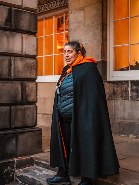 Tour guide leading an evening group in Edinburgh Old Town.