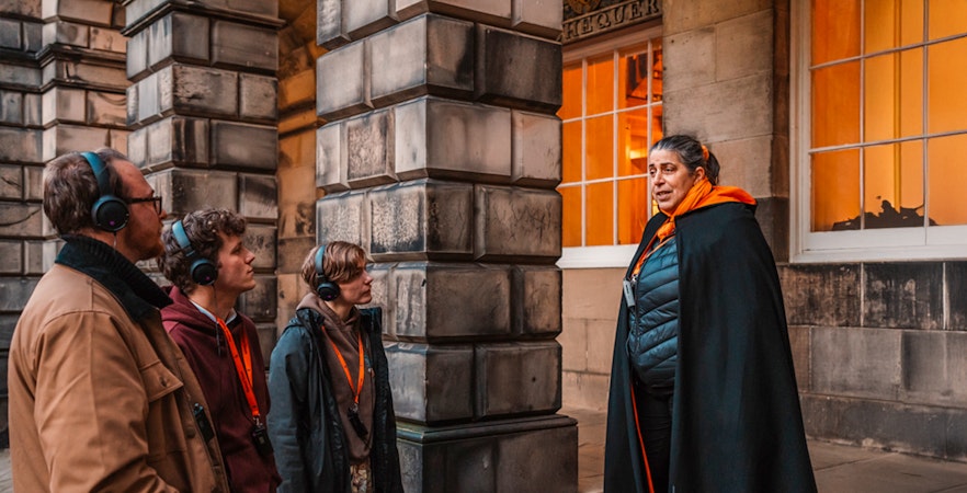 Tour guide leading an evening group in Edinburgh Old Town.