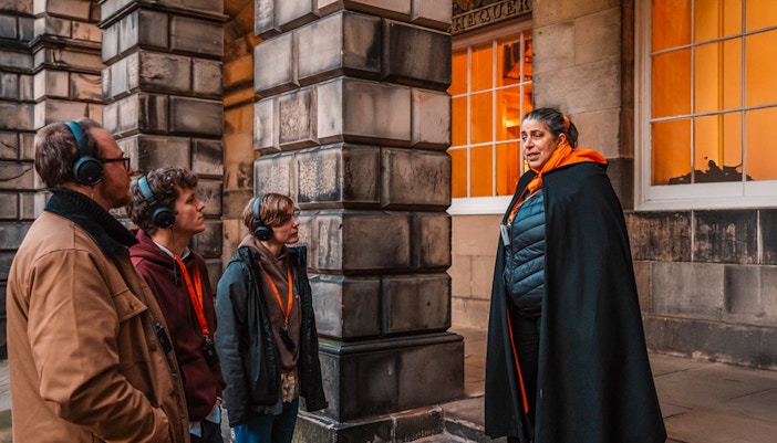 Tour guide leading an evening group in Edinburgh Old Town.