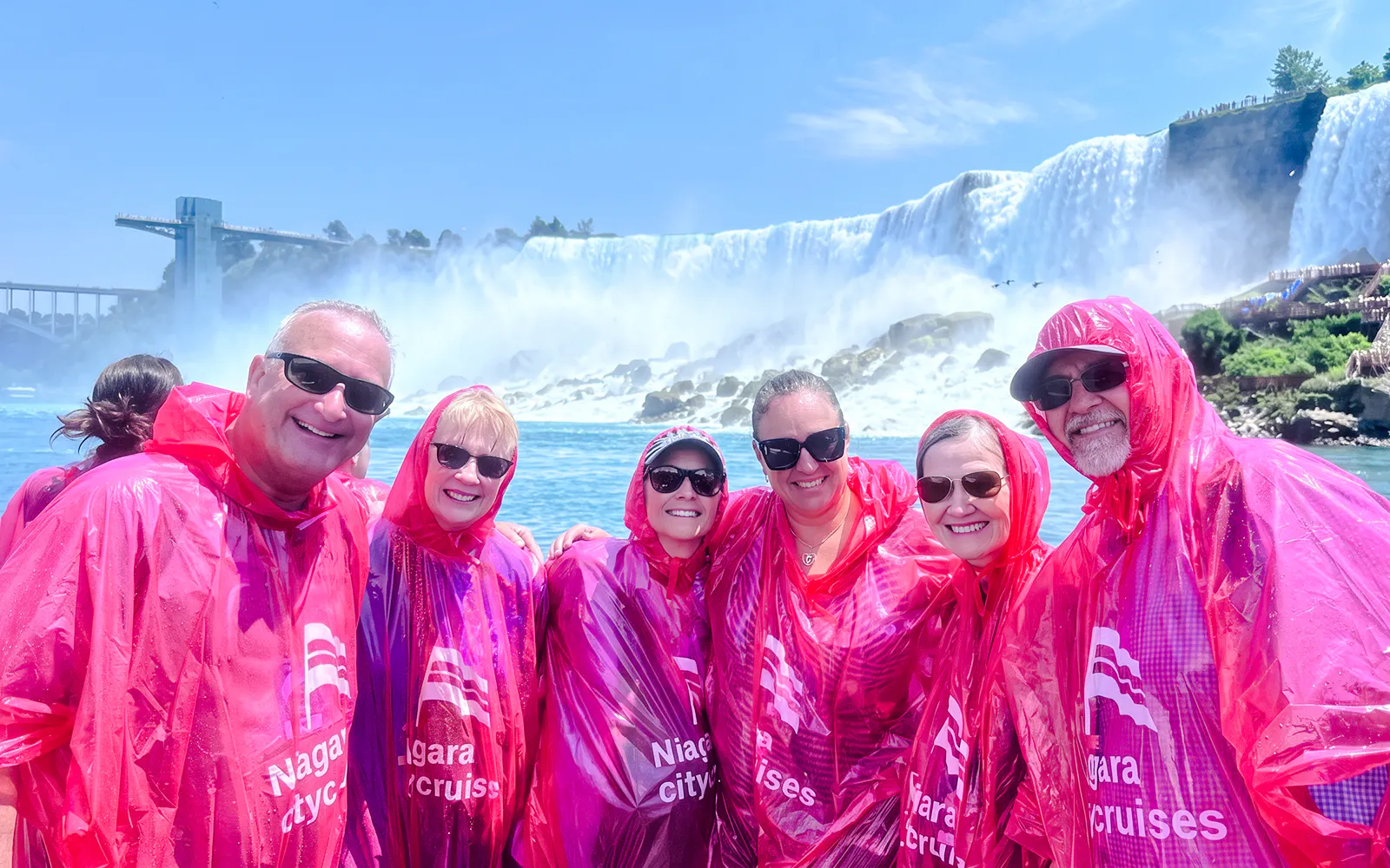 Visitors in red ponchos on a Niagara Falls boat tour with the waterfall in the background.