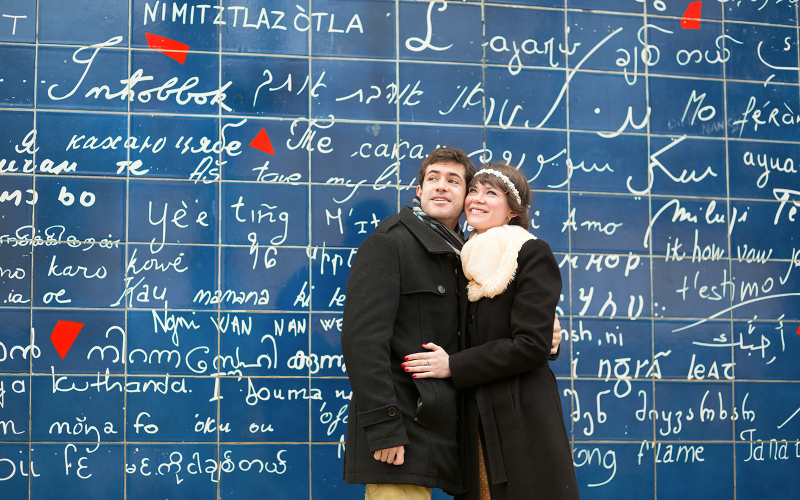 Couple standing in front of the Wall of Love in Montmartre, Paris.