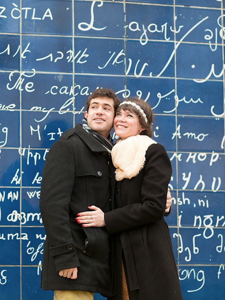 Couple standing in front of the Wall of Love in Montmartre, Paris.