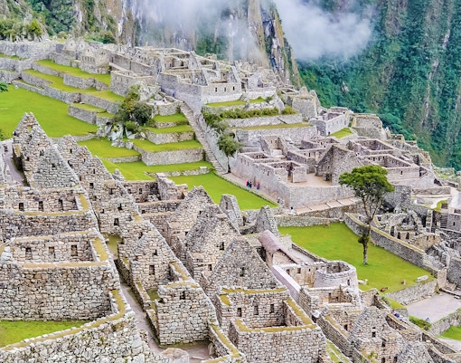 Machu Picchu ruins with terraced stone structures and lush greenery, Peru.