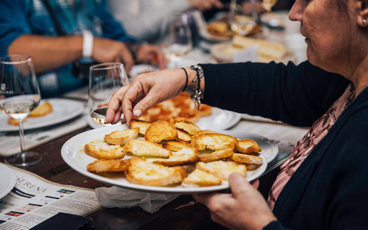 Person serving bruschetta during a Tuscany food tour.
