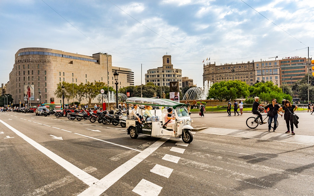 Tuk tuk driving through Plaça de Catalunya in Barcelona.