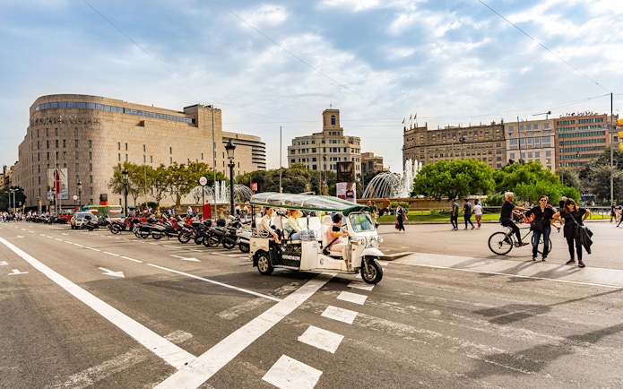Tuk tuk driving through Plaça de Catalunya in Barcelona.