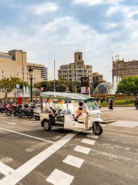 Tuk tuk driving through Plaça de Catalunya in Barcelona.