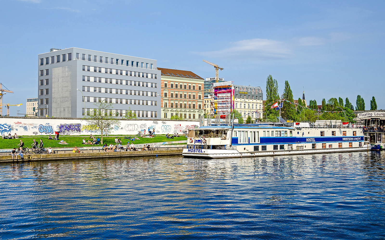 River Spree with East Side Gallery murals and boat in Berlin.