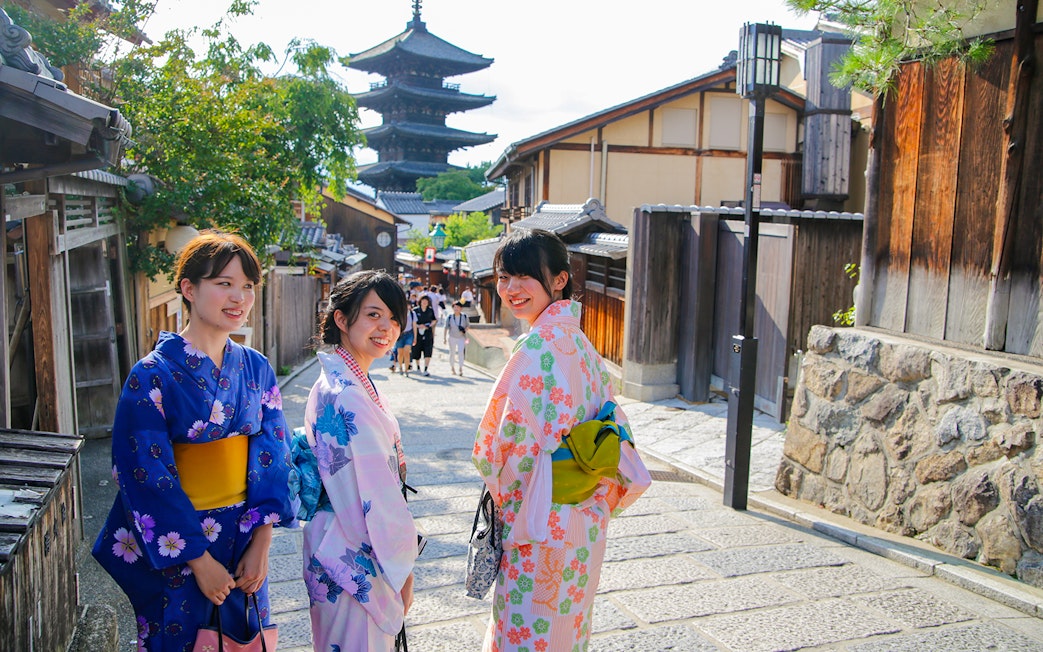 Women in kimonos walking in historic Kyoto street with Yasaka Pagoda in the background.